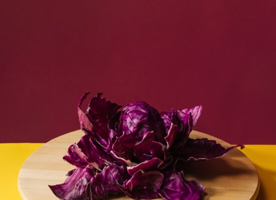 Purple cabbage on wooden board, yellow and burgundy background.