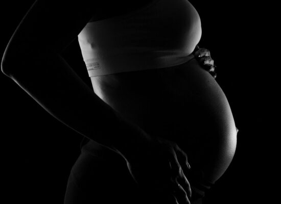 A silhouette of a pregnant person cradling their belly.