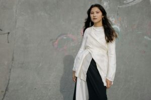 A person stands in front of a graffiti-covered concrete wall.