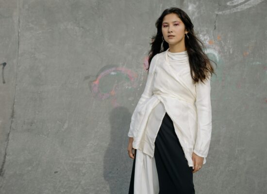 A person stands in front of a graffiti-covered concrete wall.