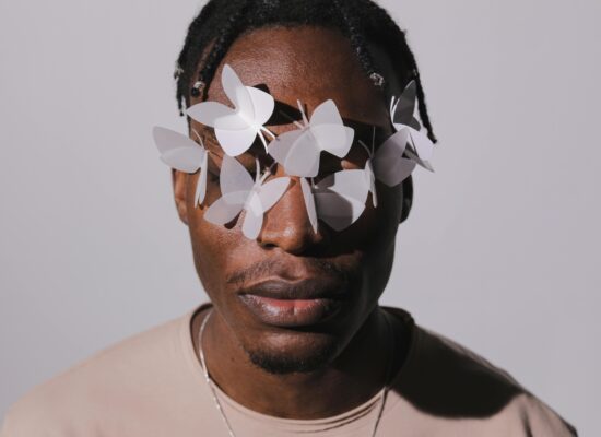 Person with paper butterflies on face, neutral background, artistic style.