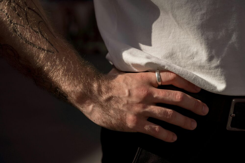 Close-up of a tattooed arm and hand with a ring.