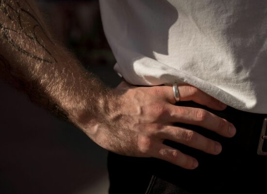 Close-up of a tattooed arm and hand with a ring.
