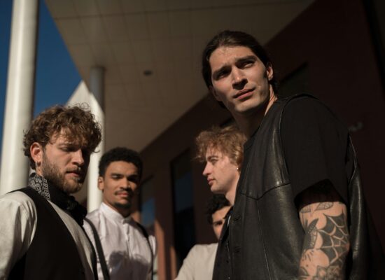 A group of young men stand outside a modern building.