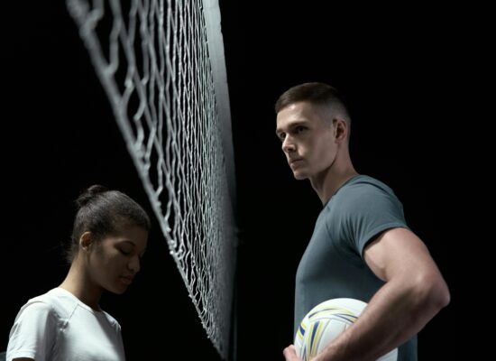 Two people stand on opposite sides of a volleyball net.