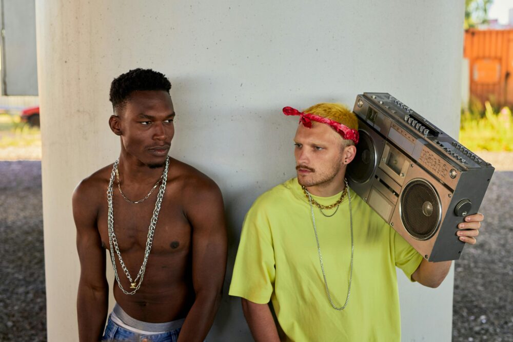 Two people standing by a pillar, one holding boombox.