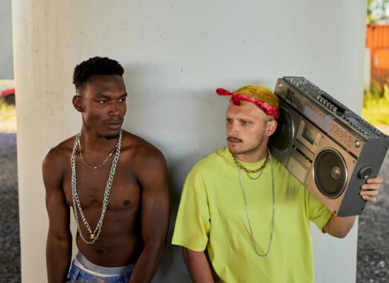 Two people standing by a pillar, one holding boombox.