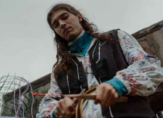 A person with long hair wearing a patterned jacket and blue collar.