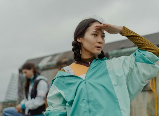 A person shields their eyes, looking into the distance.