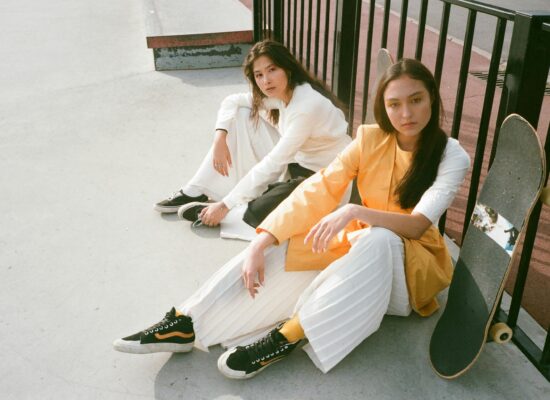Two people sitting with skateboards at a skatepark.