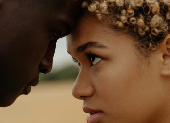 Two people touch foreheads, gazing intently at each other.