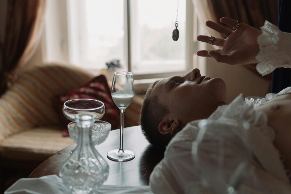 Person lying on table, glassware, pendant, soft natural light.