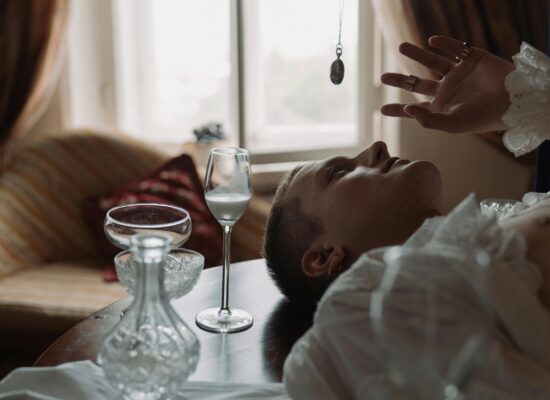 Person lying on table, glassware, pendant, soft natural light.