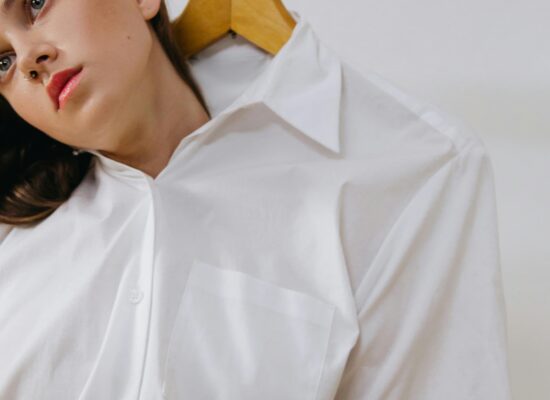 Person in white shirt with hanger, head tilted sideways.