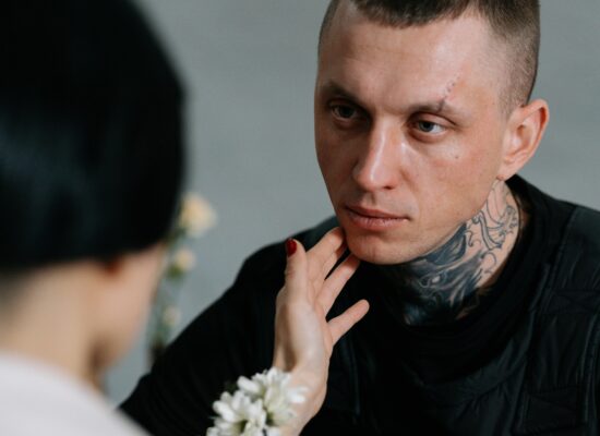 Person with tattoos being gently touched on the face, emotional moment.