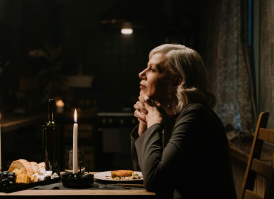 Person sitting at candlelit dinner table, appearing thoughtful and serene.