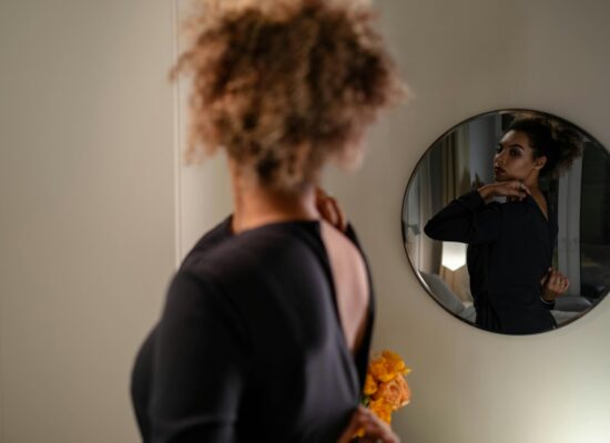 Person adjusting dress in front of mirror, holding flowers.