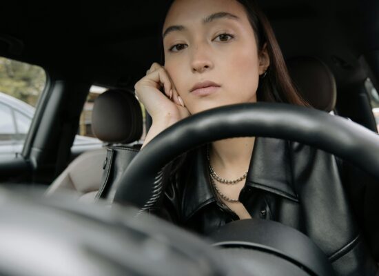 Person sitting in a car, looking thoughtful behind steering wheel.