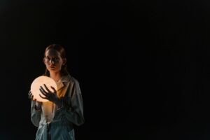 A person holds a glowing orb against a dark background.