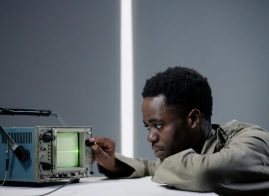 Person adjusting an oscilloscope, focused on the green display.