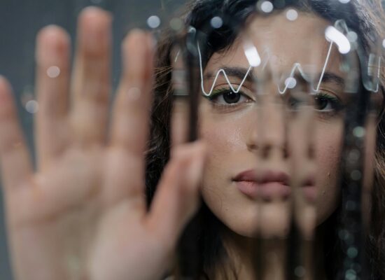 Person behind glass with hand raised, reflections and light distortions.