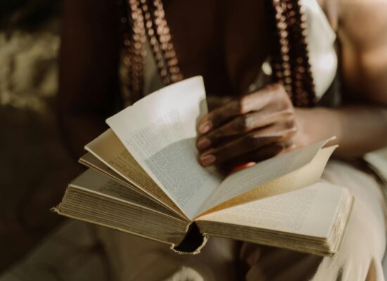 Person turning pages of an old book in soft light.