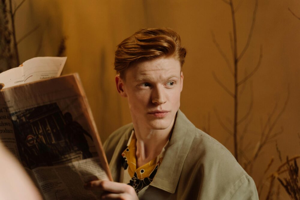 Person holding a newspaper, looking to the side, warm background.