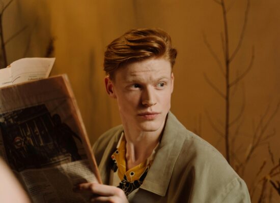 Person holding a newspaper, looking to the side, warm background.