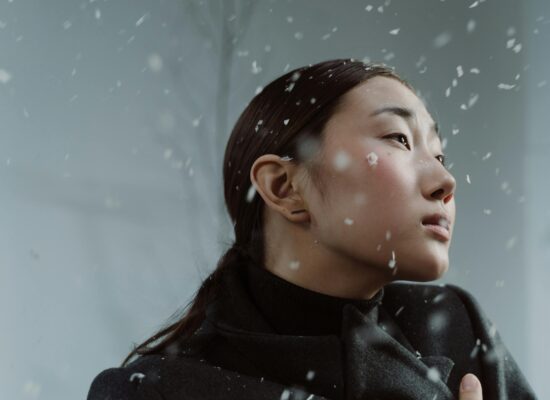Person in winter coat with snowflakes falling around them.