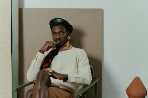 Person wearing a black beret and scarf, sitting in a chair.