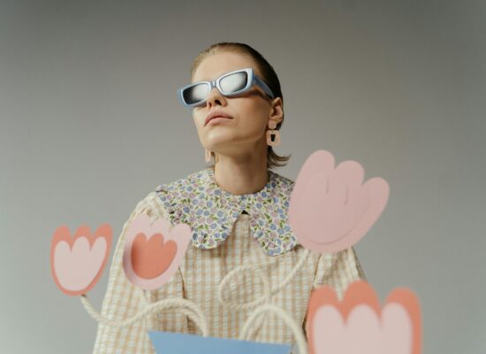 Person wearing sunglasses and a floral collar shirt with paper flowers.