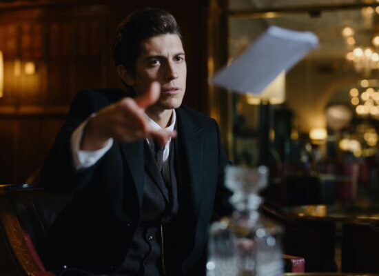 A man in a suit throws a paper in a dimly lit room.