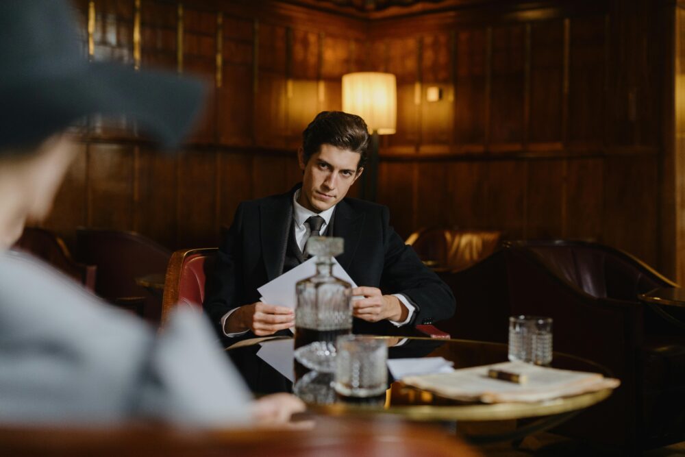 A man in a suit sits at a table with drinks.