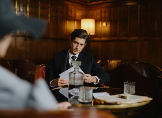 A man in a suit sits at a table with drinks.