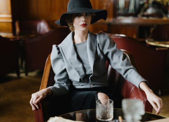 A person in a hat and gray suit sits in a leather chair.