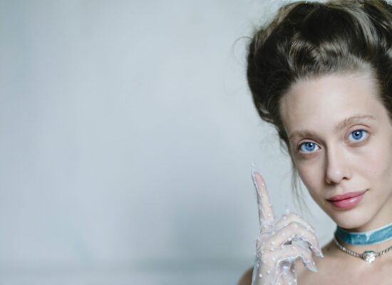 A person in vintage attire with a feather in their hair.