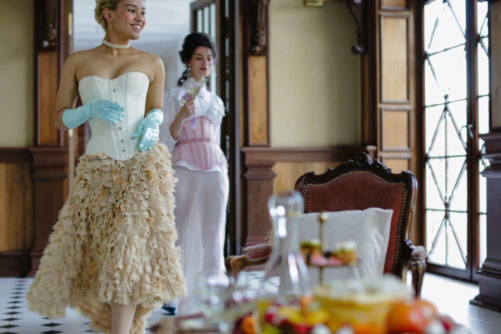 People in historical attire in a room with a tea set.
