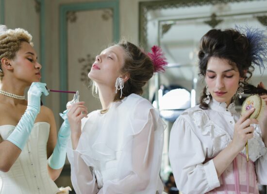 Three women in vintage attire preparing for an event.