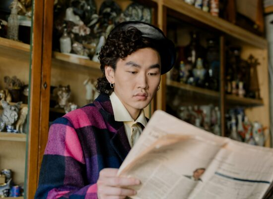 Person in a beret and plaid jacket reading a newspaper.