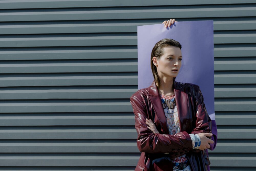 Person holding a purple board in front of a grey wall.