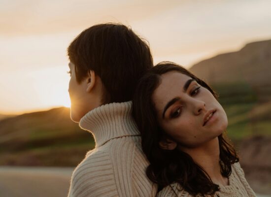 Two people leaning on each other at sunset with warm light.