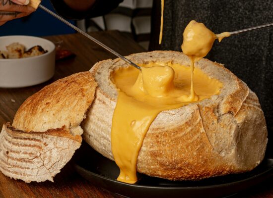 Person pouring oil and vinegar onto a white plate.