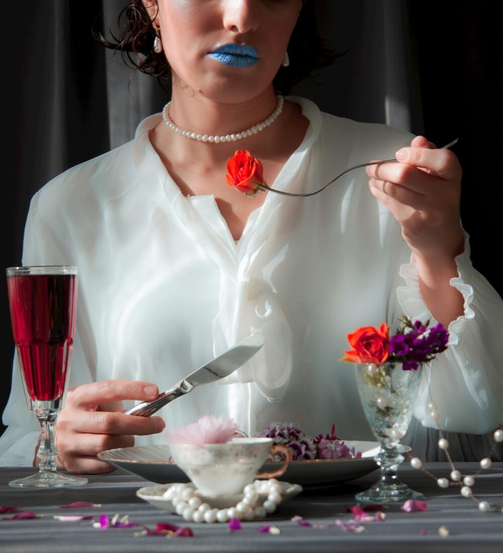 Person in white shirt sitting, pinching nose, looking stressed.