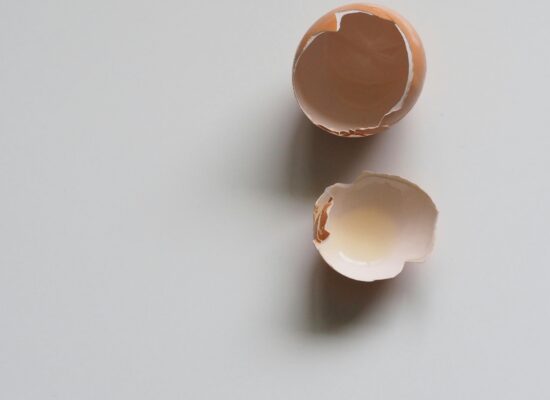Two broken eggshell halves on a plain white surface.