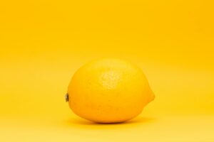 A single lemon on a bright yellow background, minimalistic style.
