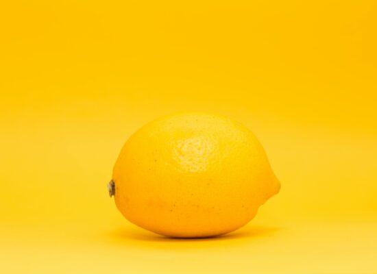 A single lemon on a bright yellow background, minimalistic style.