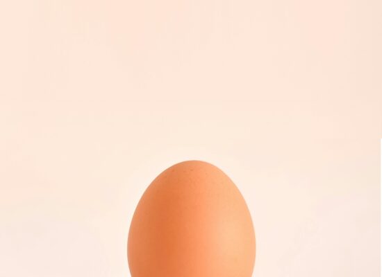 Brown egg balanced on two crossed forks, minimal background.