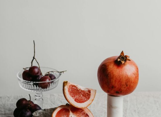 Assorted fruits including grapefruit, grapes, and pomegranate on table.