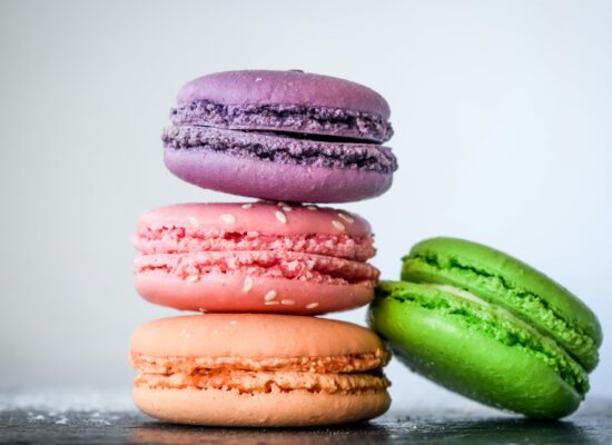 Four colorful macarons stacked on each other against white background.