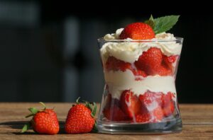 Glass filled with strawberries and cream, garnished with mint leaf.